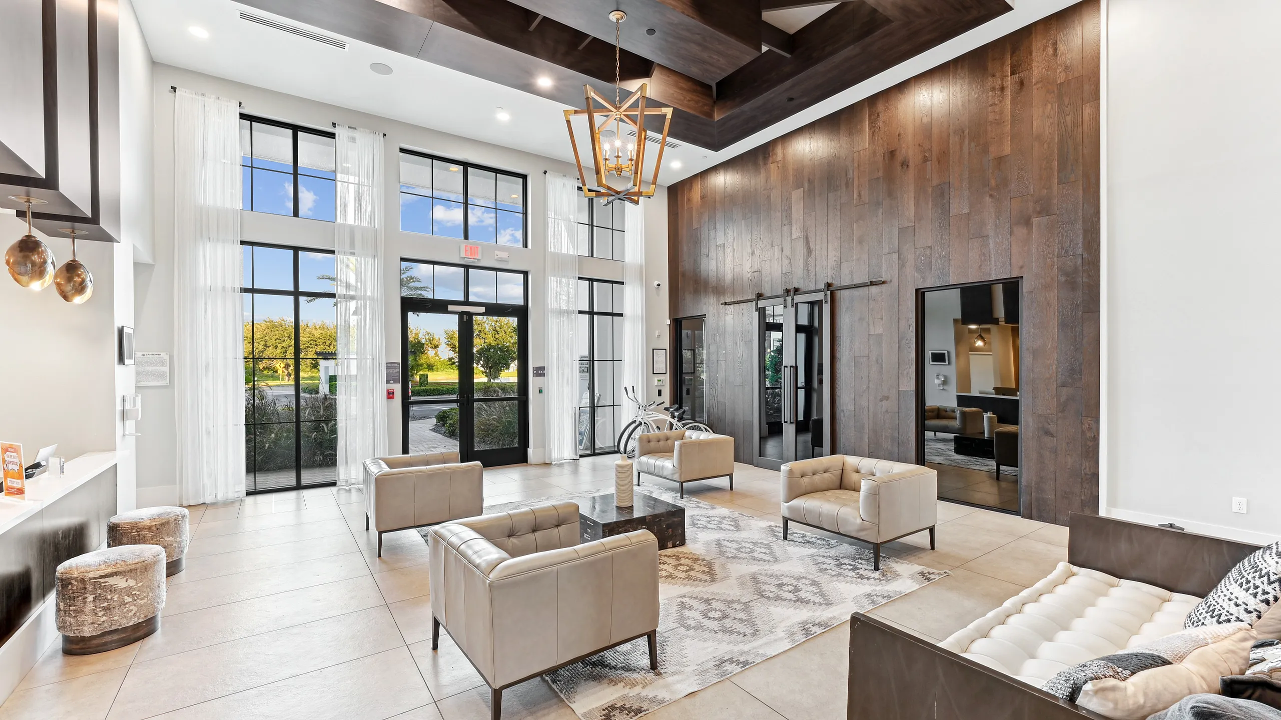 Modern lobby with elegant wooden accents, high ceilings, and stylish seating, featuring large windows with a scenic view.