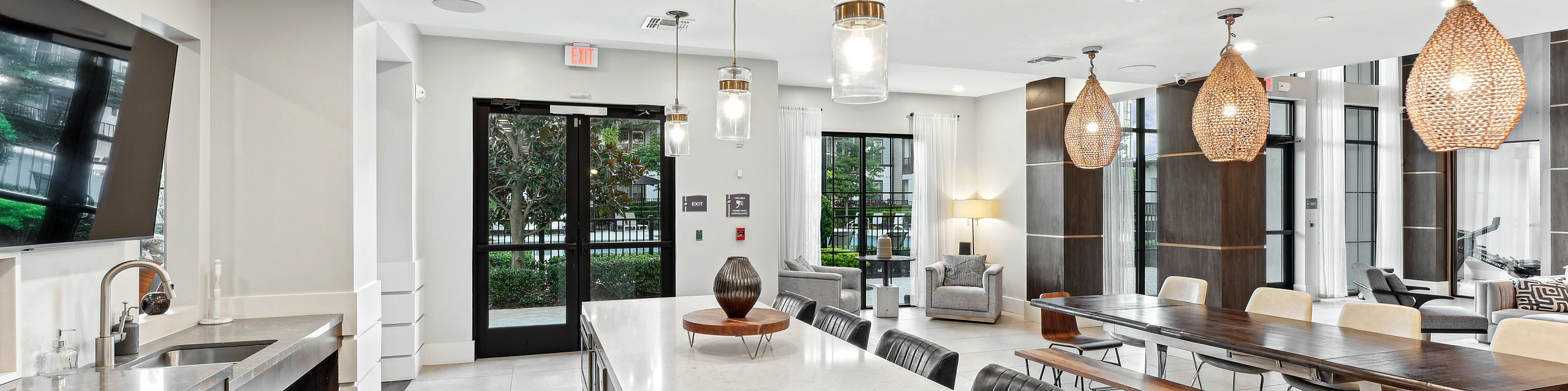 Contemporary open-concept kitchen and dining area featuring a large marble island, chic lighting fixtures, and elegant seating arrangement with natural light.