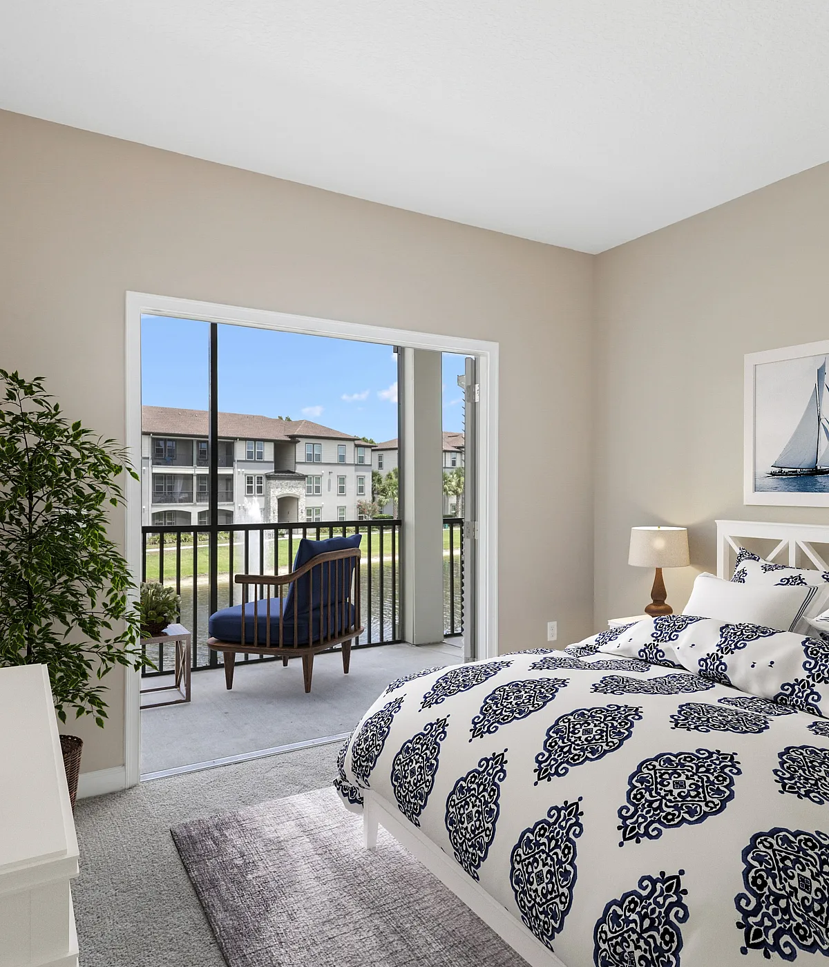 Bright and cozy bedroom with elegant decor, featuring nautical-themed artwork and a large window revealing a scenic balcony view.