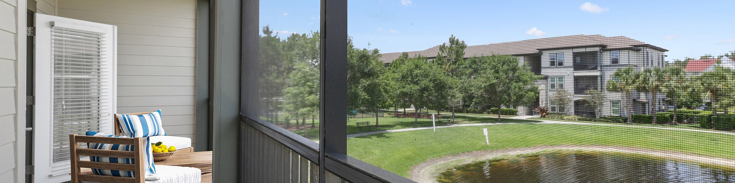 Inviting balcony with cozy seating overlooking serene pond and lush greenery, perfect for relaxation.