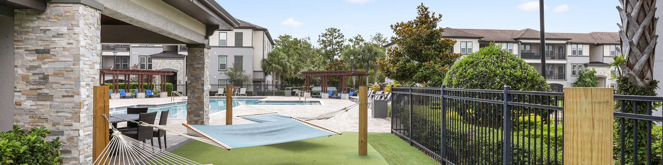 Peaceful outdoor space with relaxing hammocks and a stylish poolside area, surrounded by lush greenery and modern architecture.