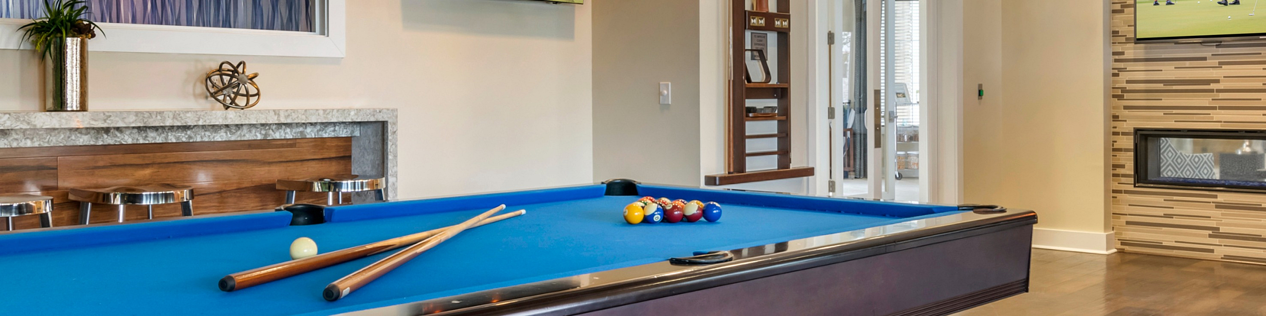 Luxury apartment game room with a modern billiards table, stylish pendant lighting, and sleek bar seating, creating a perfect blend of entertainment and elegance.