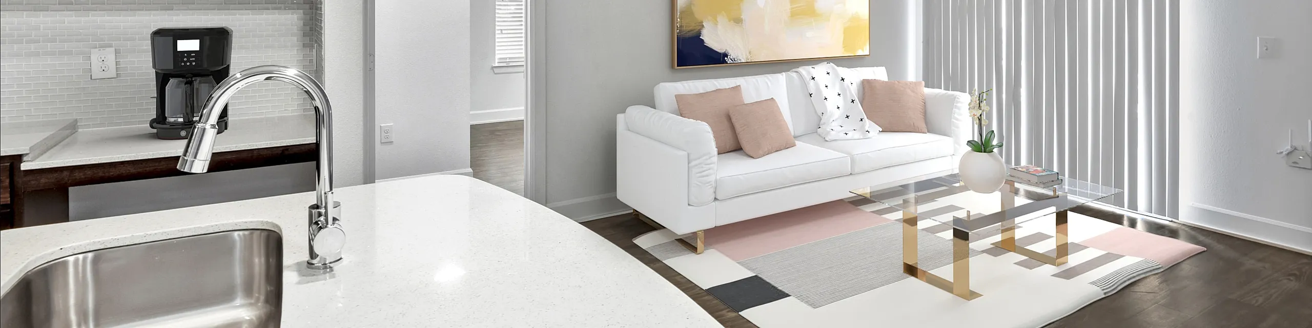 Bright modern living area with sleek kitchen design, cozy white sofa, artistic wall art, and a stylish glass coffee table, ideal for contemporary living.