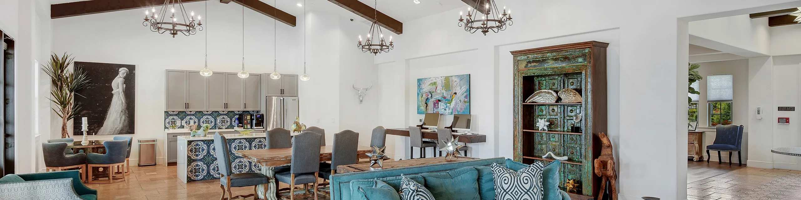 Charming and spacious living area with elegant chandeliers, rustic wood beams, and a cozy teal sofa set. Features an open dining area and stylish accents, offering a perfect blend of comfort and sophistication.