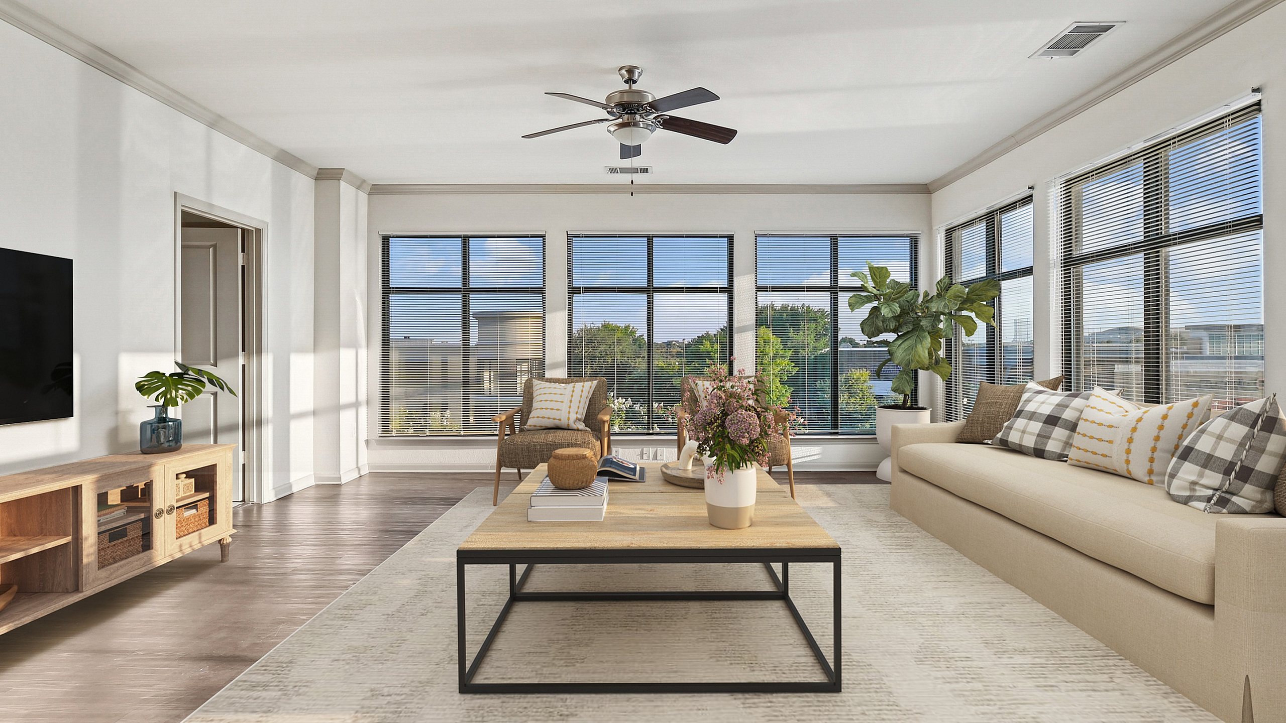 Bright and spacious living room with modern decor, featuring large windows, a comfortable beige sofa, stylish coffee table, and beautiful greenery accents.