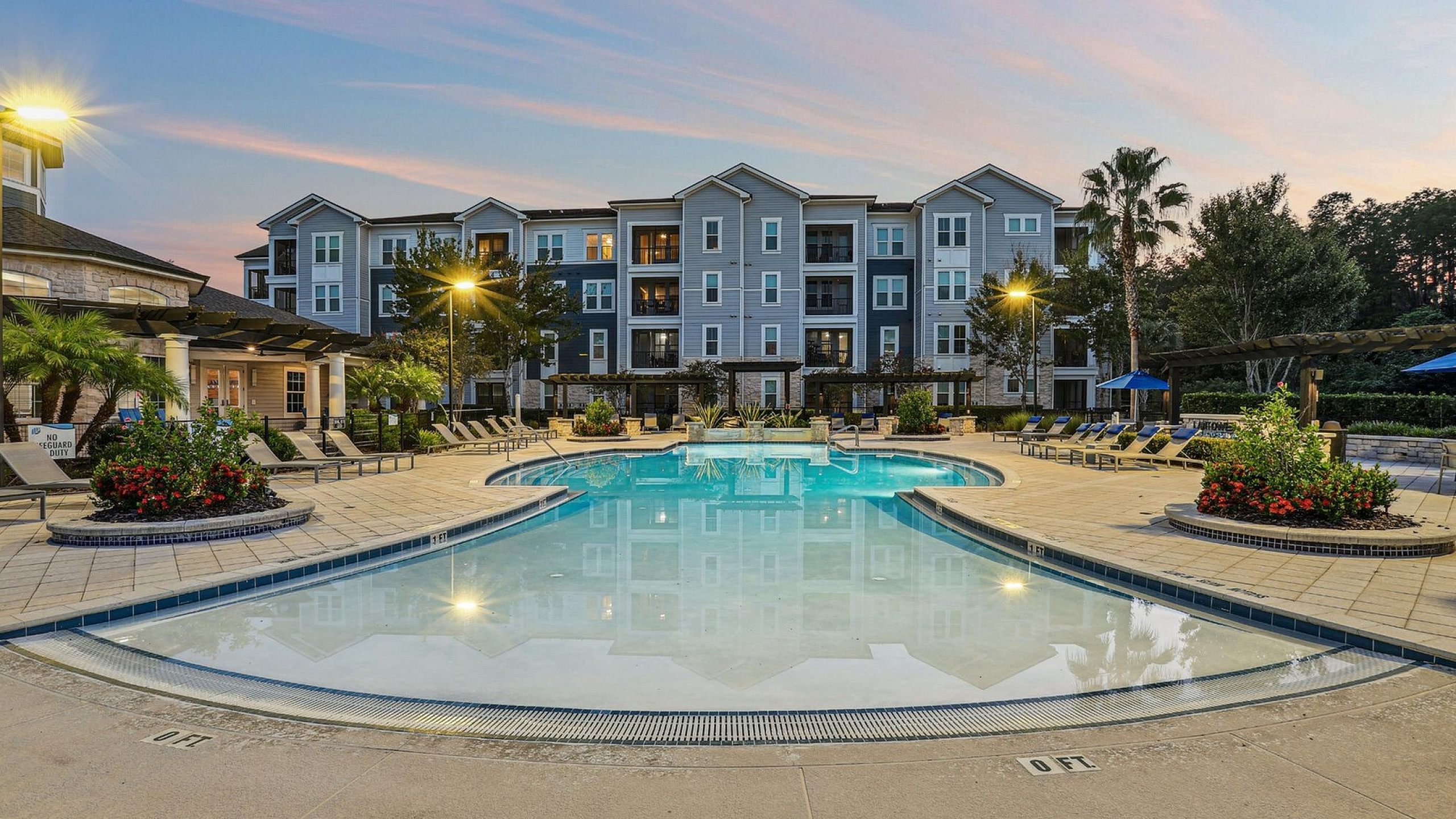 Luxurious apartment complex with a shimmering outdoor pool and elegant landscaping, perfect for relaxation and leisure.