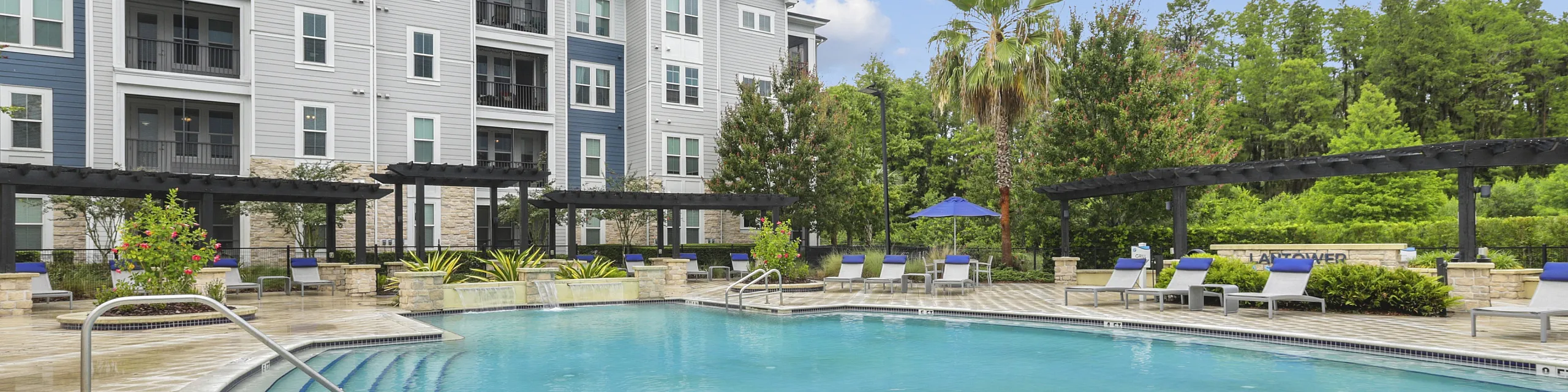 Luxurious apartment complex with a sparkling pool, modern architecture, and lush greenery, perfect for relaxation and leisure.