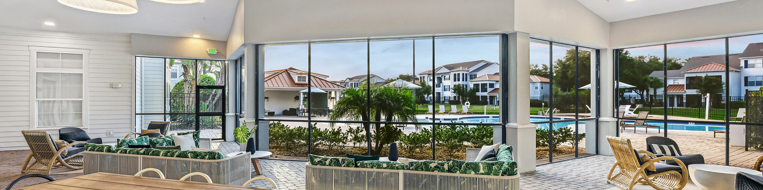 Beautiful indoor-outdoor living space with modern design, featuring comfortable seating, large windows overlooking a pool, and elegant lighting.