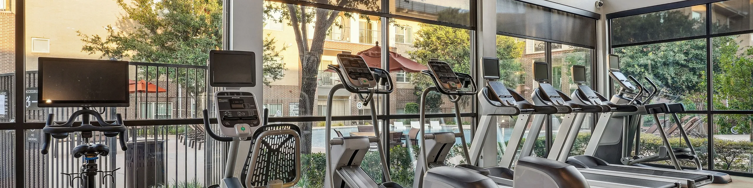 Bright and modern fitness center with cardio machines and floor-to-ceiling windows overlooking a serene courtyard.