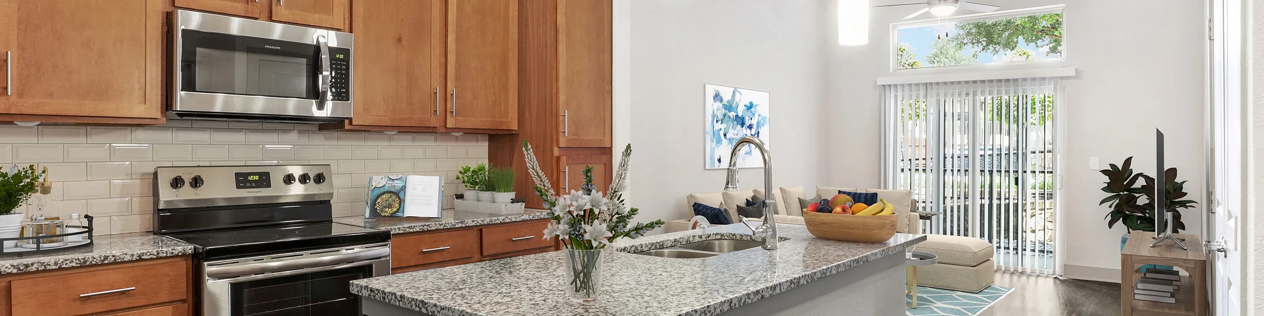 Modern kitchen with sleek granite countertops adjacent to a cozy living room, featuring elegant wooden cabinets and natural light pouring in through large windows.