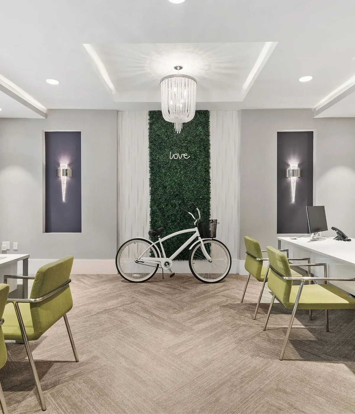 Chic office space featuring modern decor with elegant lighting, vibrant green chairs, and a decorative vertical garden adding a touch of nature.