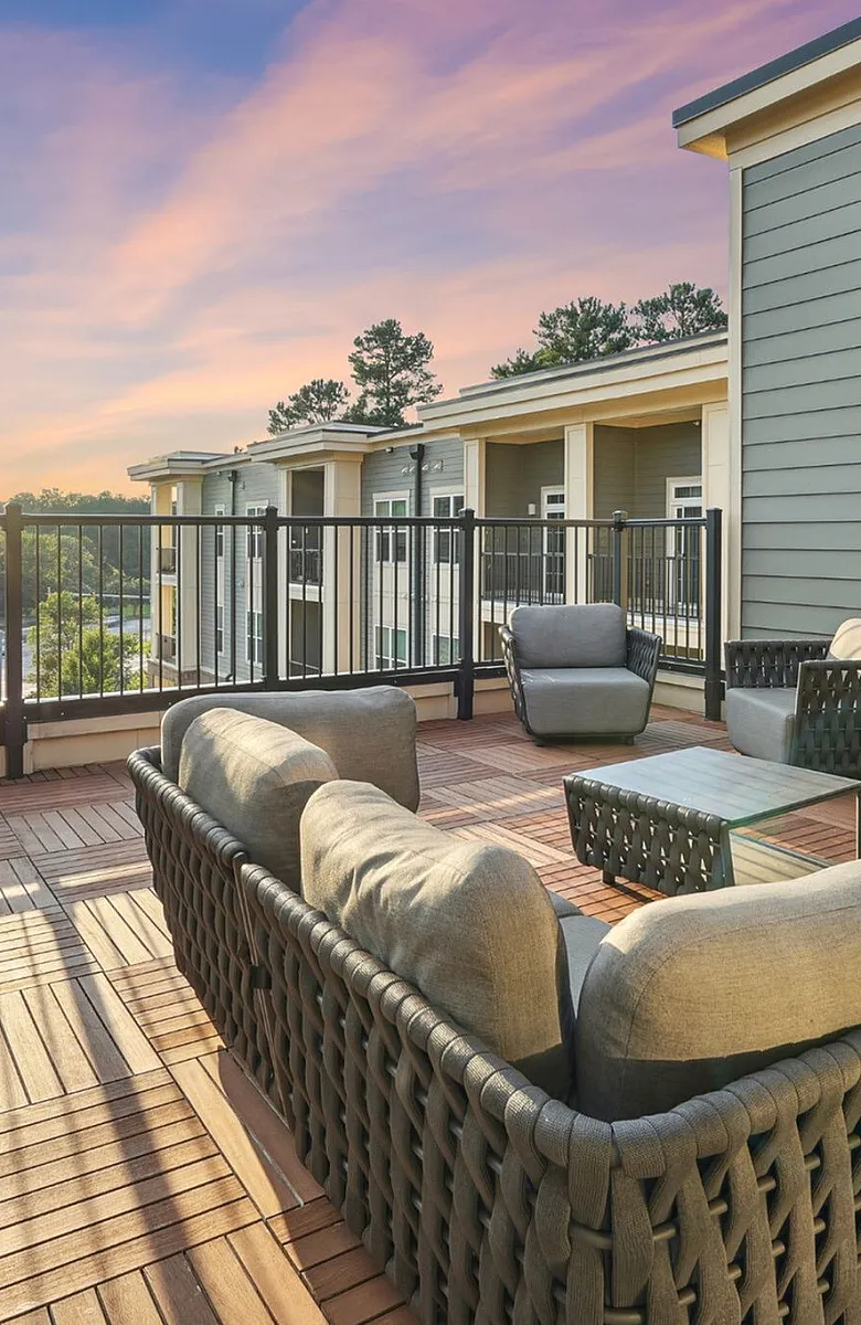 Spacious outdoor terrace with stylish wicker seating, overlooking a scenic sunset view.
