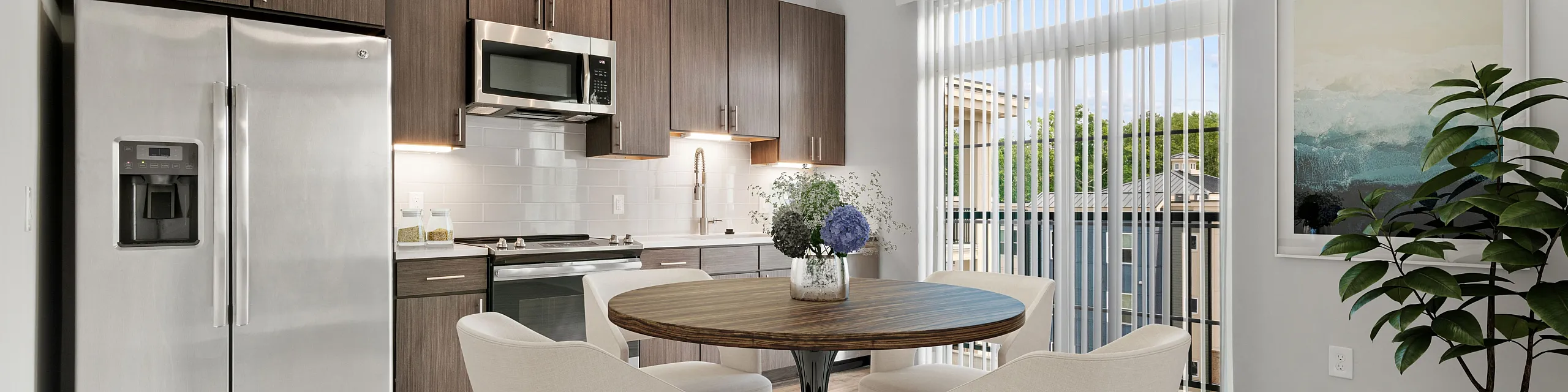 Modern kitchen-dining area with stainless steel appliances, elegant cabinetry, and a cozy round table. Bright space with large windows and chic decor.