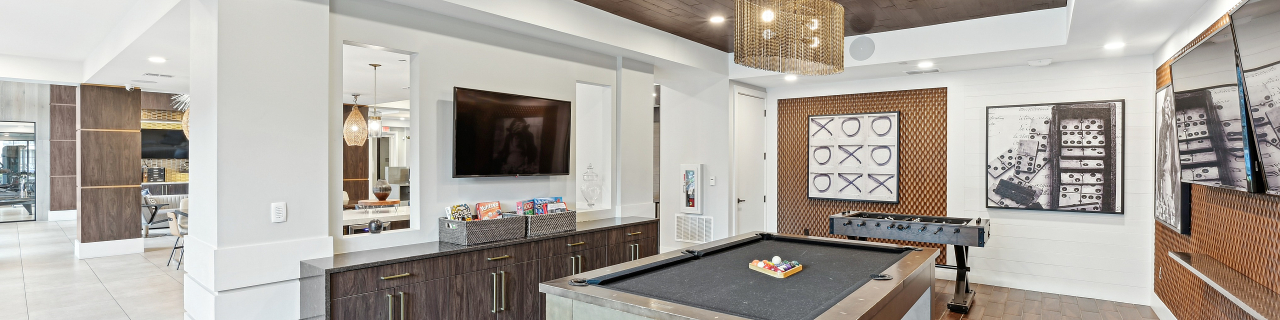 Luxurious game room featuring a sleek pool table, foosball, and modern entertainment area with stylish wooden accents.