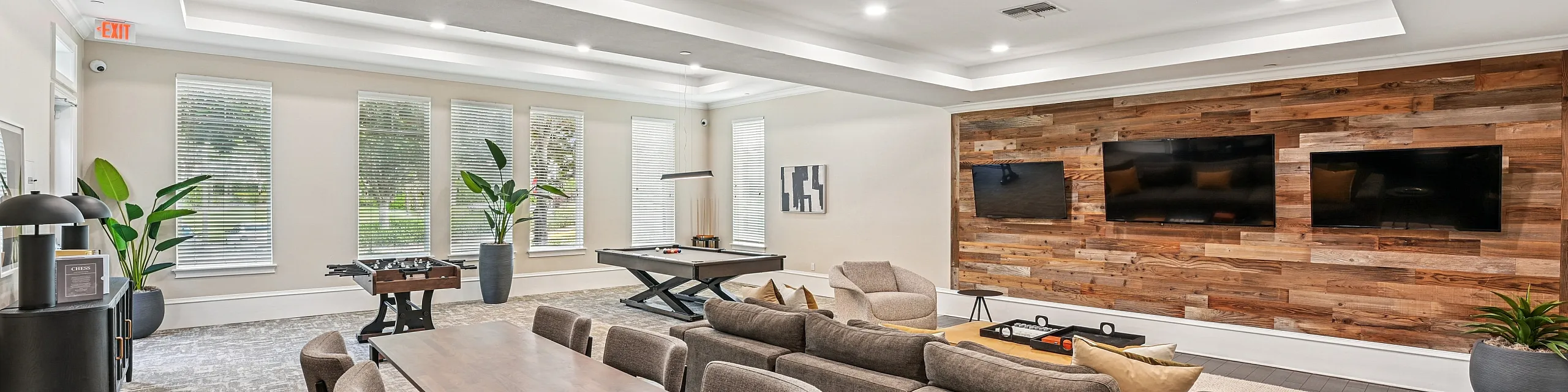 Modern entertainment lounge with plush seating, wood accent wall, and sleek game area.