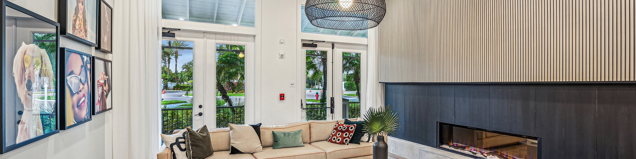 Modern apartment living room with chic furniture, elegant fireplace, and stylish artwork. Large windows offer a lush garden view, enhancing the cozy, inviting atmosphere.