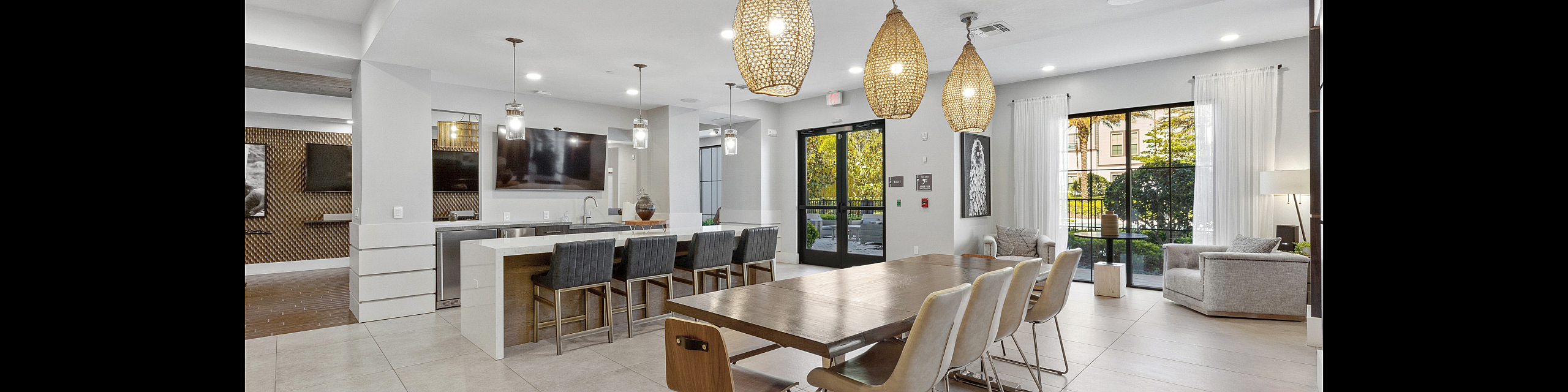 Chic communal space with modern open-design kitchen, elegant dining area, and cozy seating by large sunlit windows, perfect for socializing.