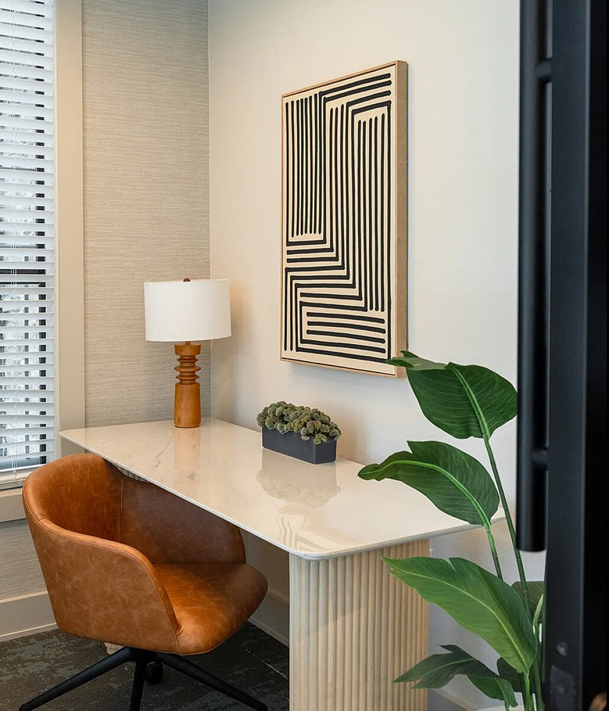 Elegant apartment lobby featuring a modern chandelier, plush blue armchairs, and a cozy fireplace, perfect for welcoming guests.