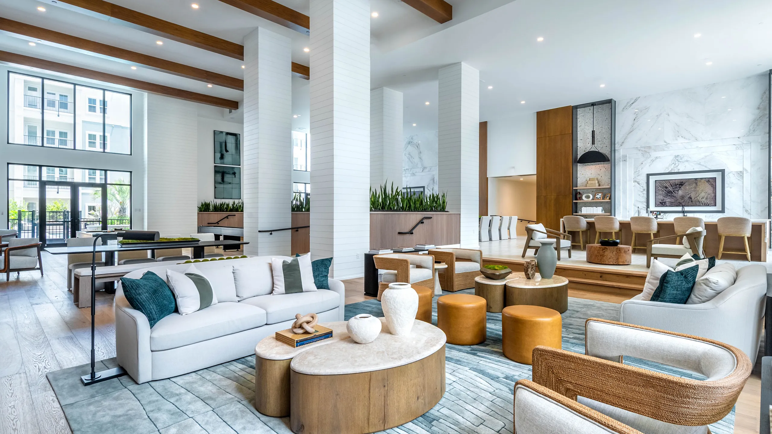 Modern community lounge with billiard tables, chic seating area, and expansive windows, offering a stylish and inviting atmosphere.