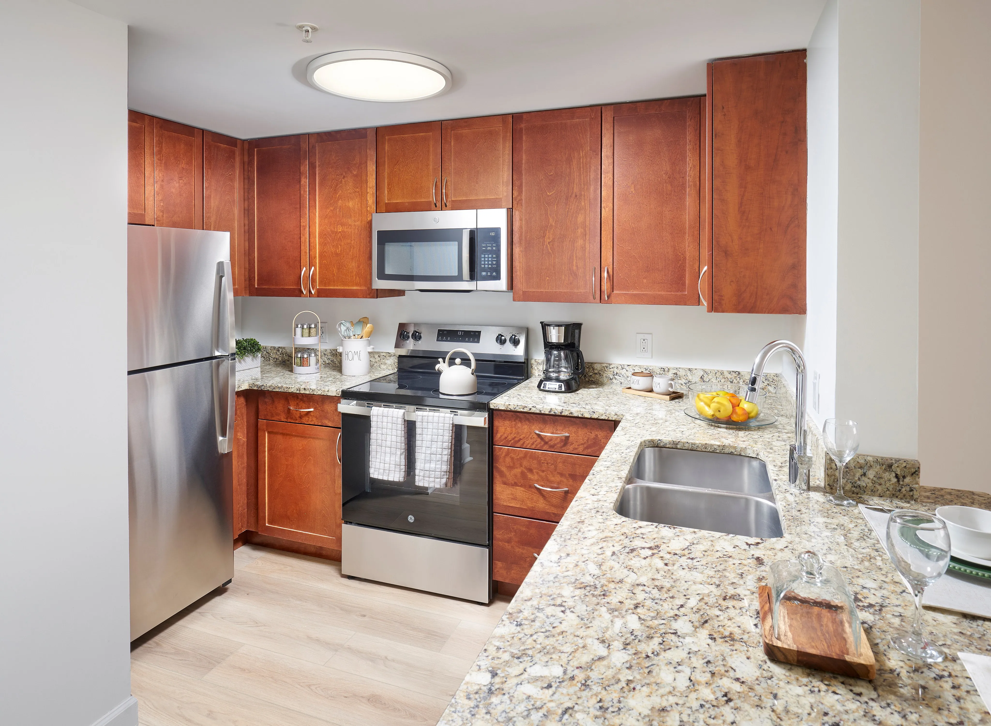 Renovated Ashton 2BR kitchen with stainless steel appliances, granite countertops, and wood-style flooring. | Meridian at Eisenhower Station | Luxury Alexandria VA Apartments