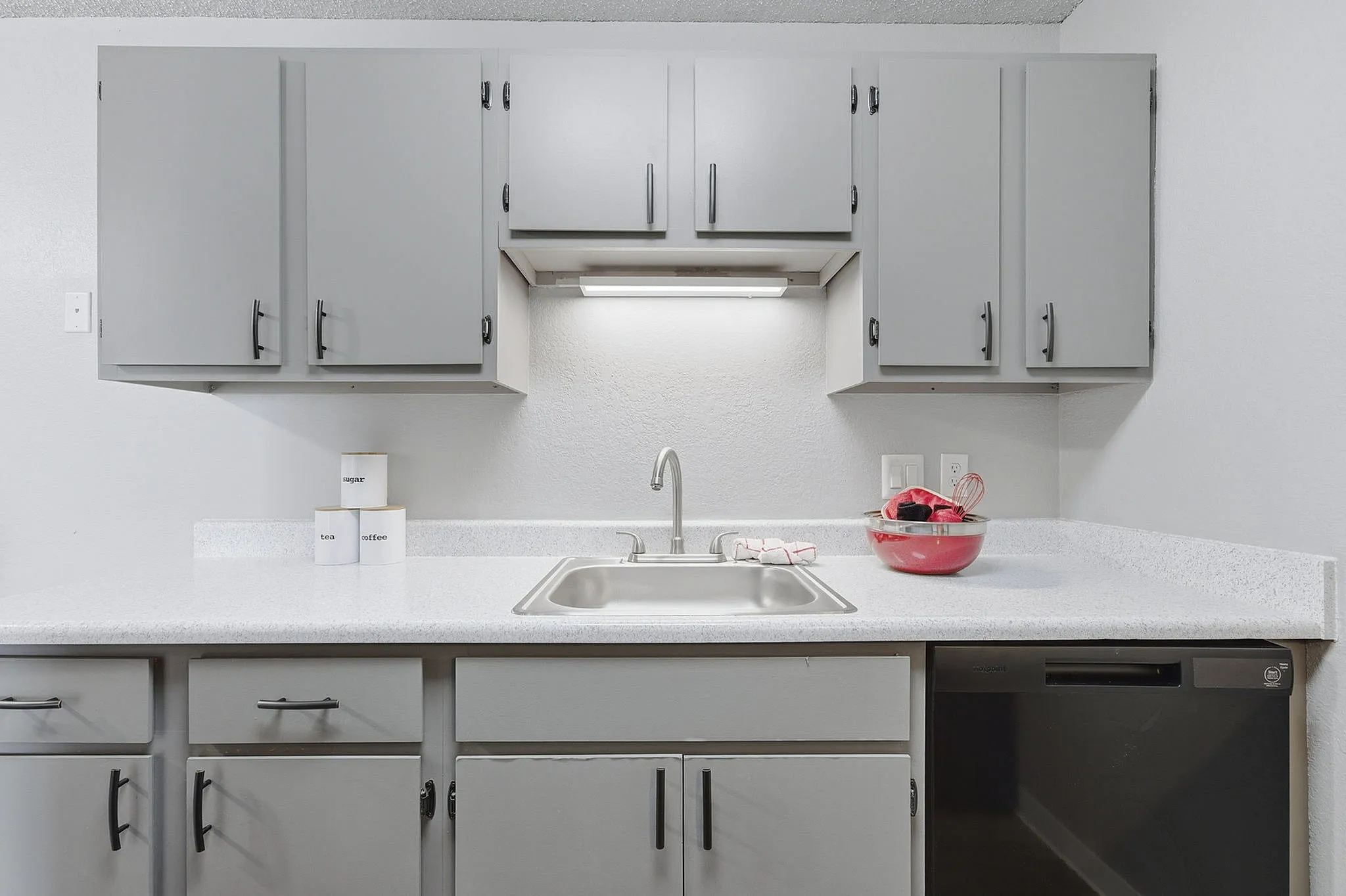 Modern kitchen featuring sleek gray cabinets, stainless steel sink, and bright countertop, ideal for culinary enthusiasts.