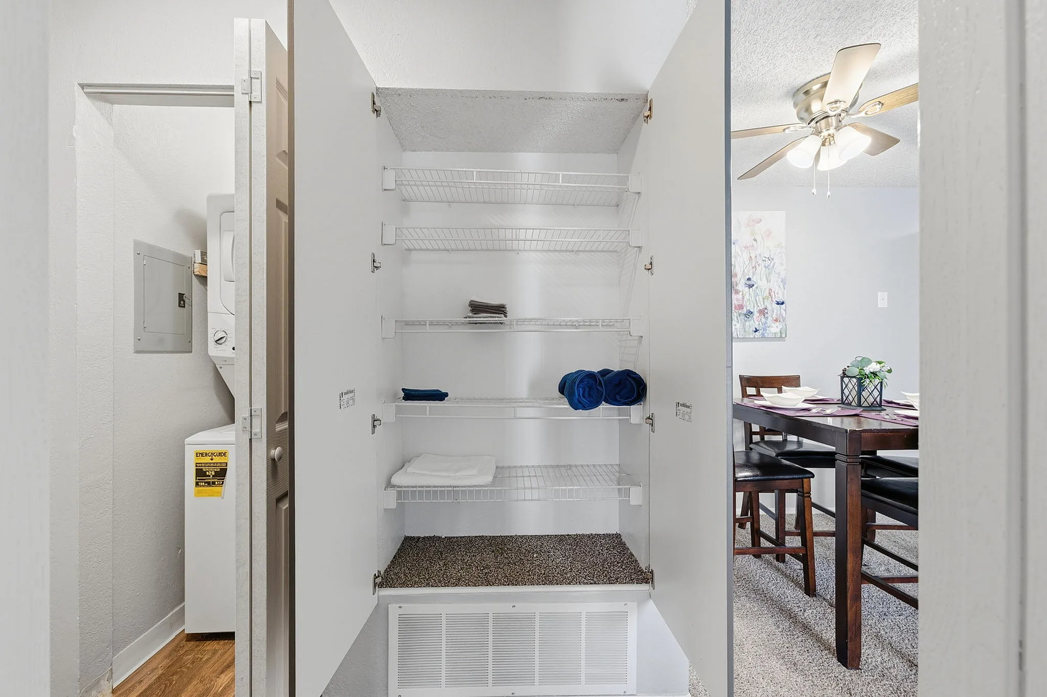 Bright and efficient laundry area with ample shelving, adjacent to a cozy dining space featuring elegant decor.