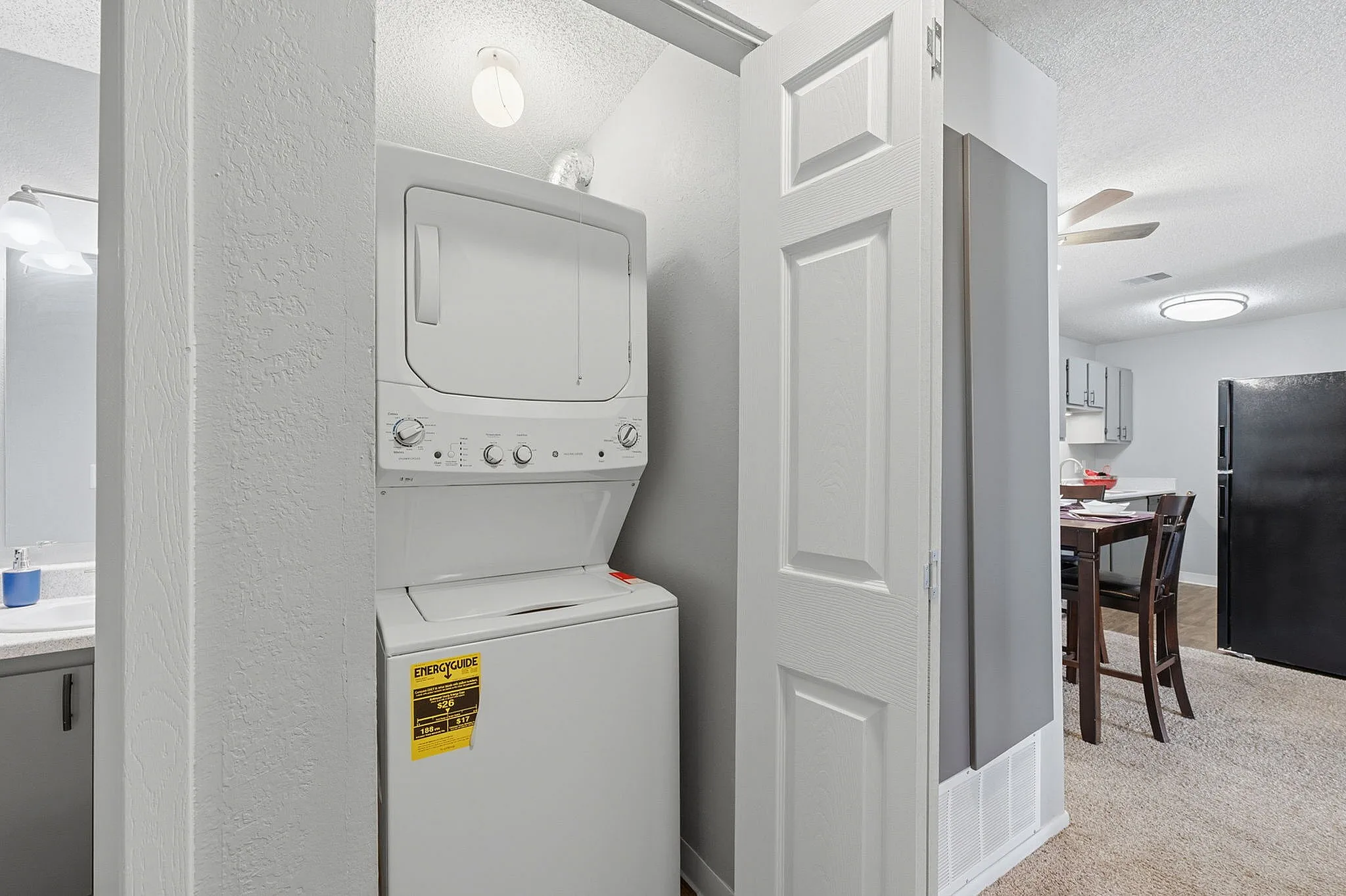 Modern apartment with in-unit stacked washer and dryer, adjacent to a bright, open kitchen and dining area for convenient living.