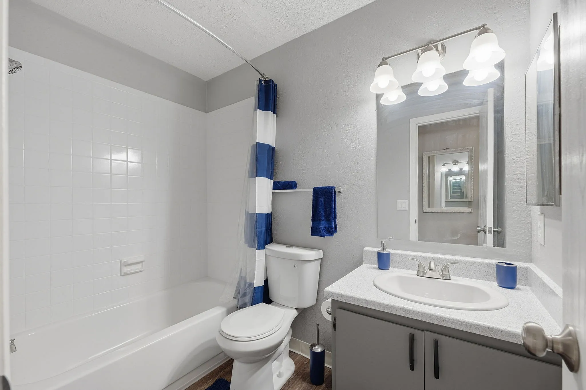 Contemporary bathroom featuring a sleek vanity, bright lighting, and a chic blue and white striped shower curtain.