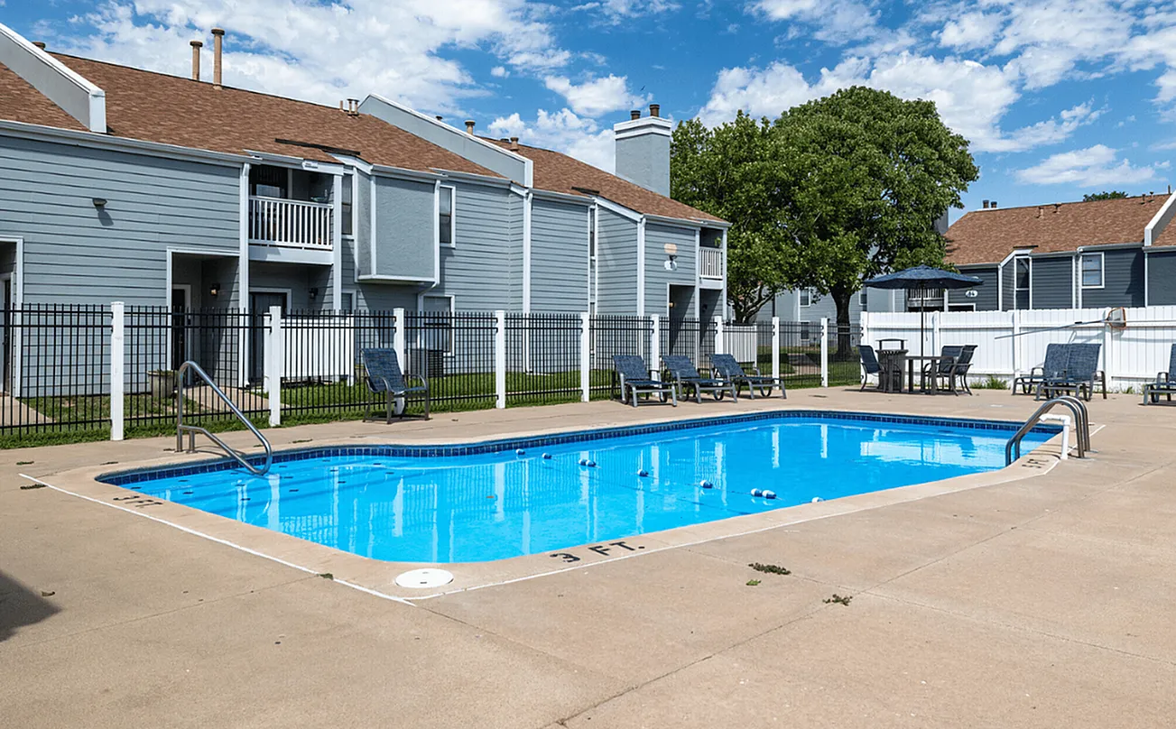 Inviting outdoor pool area with comfortable lounge chairs and vibrant blue skies at modern apartment complex.