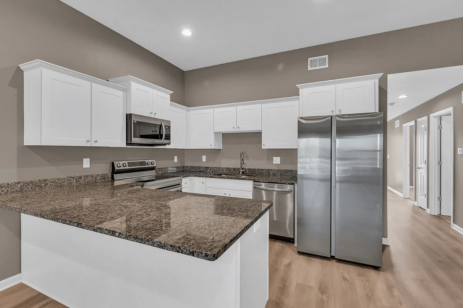 Modern kitchen with granite countertops, sleek stainless steel appliances, and abundant white cabinetry for stylish living.
