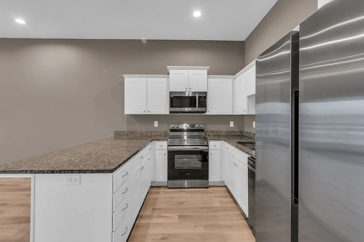 Modern kitchen with sleek stainless steel appliances, elegant granite countertops, and spacious white cabinetry.