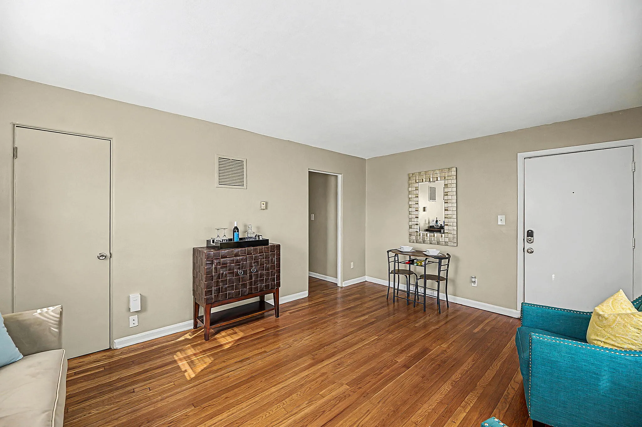 Charming living area with hardwood floors, a stylish cabinet, and a cozy dining nook, perfect for relaxation and entertainment.