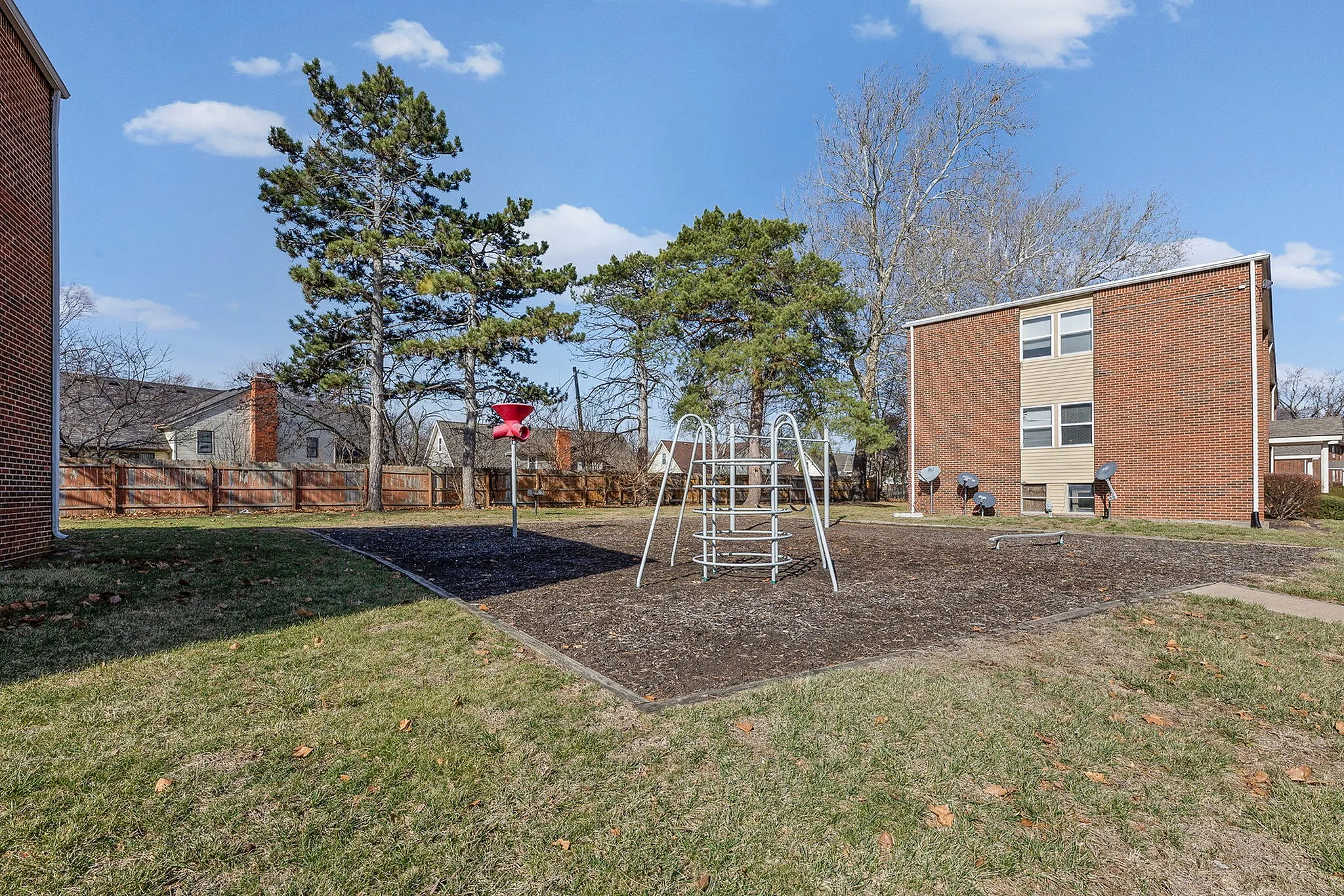 Inviting outdoor playground area surrounded by scenic green spaces and modern brick buildings, perfect for family-friendly living.