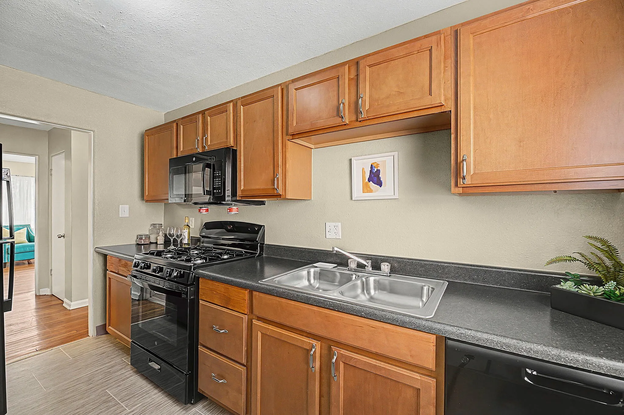Modern kitchen with sleek black appliances, wooden cabinets, and stylish countertops, offering a contemporary and functional space.