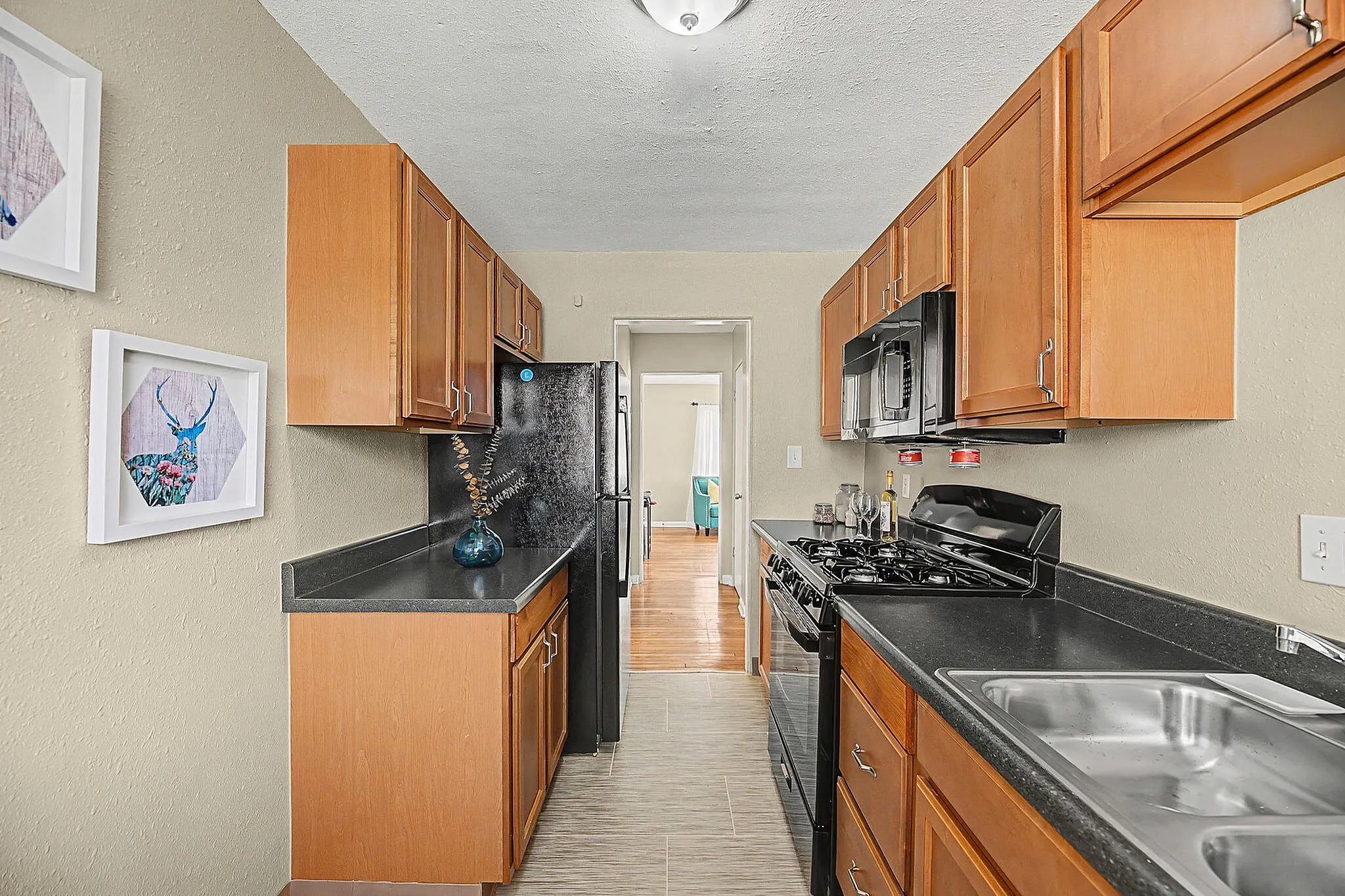 Cozy modern kitchen with sleek black countertops, wooden cabinets, and stainless steel appliances, perfect for culinary enthusiasts.