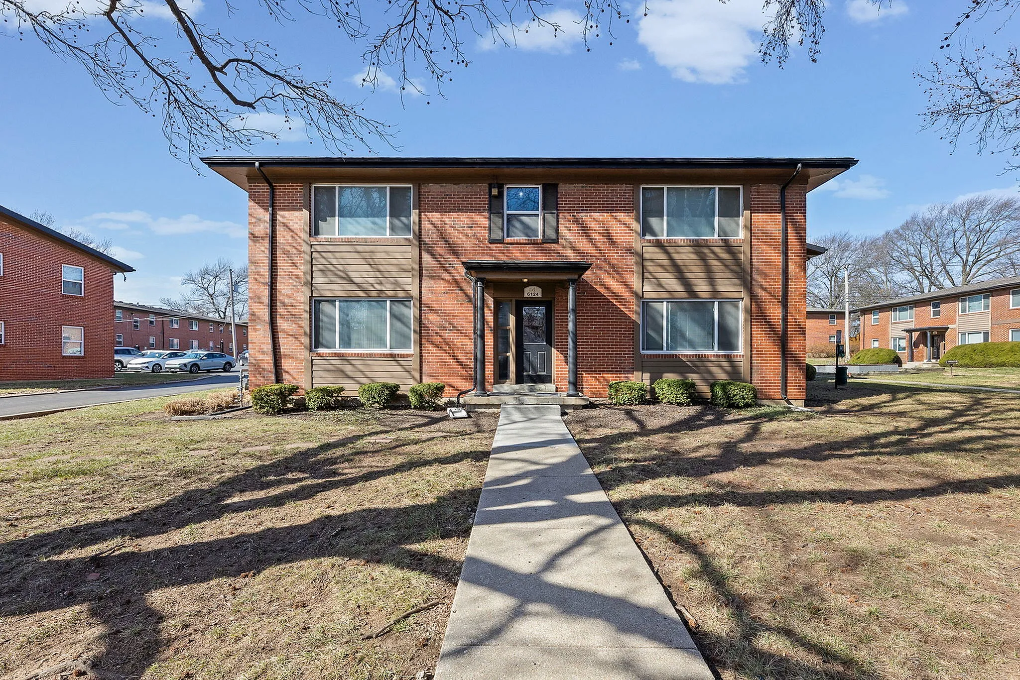 Charming red-brick apartment building with well-maintained landscaping and spacious window views.