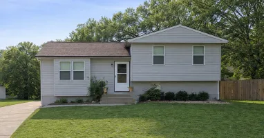 Charming single-story home with a well-maintained lawn, nestled among lush trees, offering a peaceful residential setting.