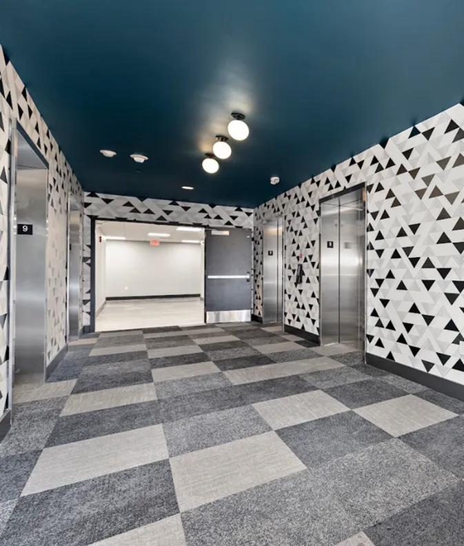 Modern apartment elevator lobby with geometric patterned walls and stylish carpeting, offering a sleek and sophisticated entrance.