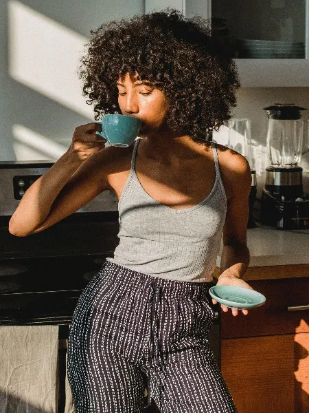 Girl in kitchen sipping coffee