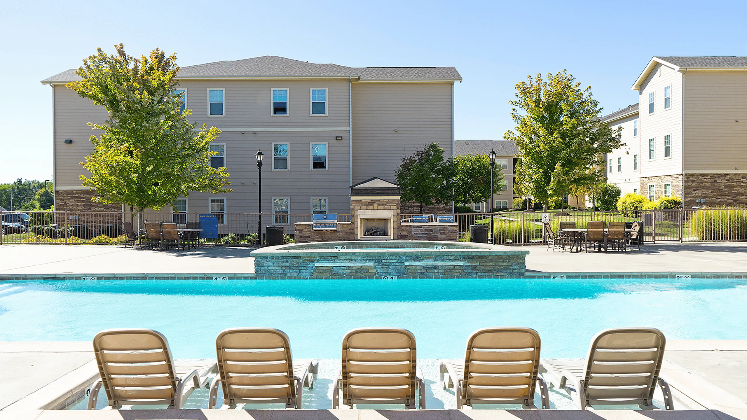 image of pool with hot tub and water full and building in background