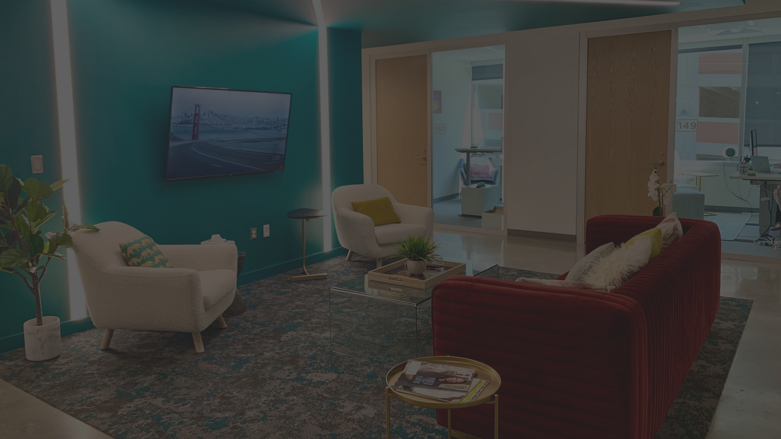 seating area with velvet couch and tv outside private offices