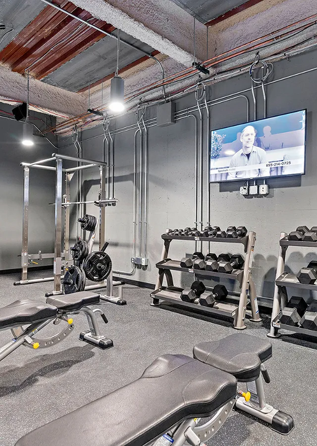 fitness center showing tv, free weights, and weight machine