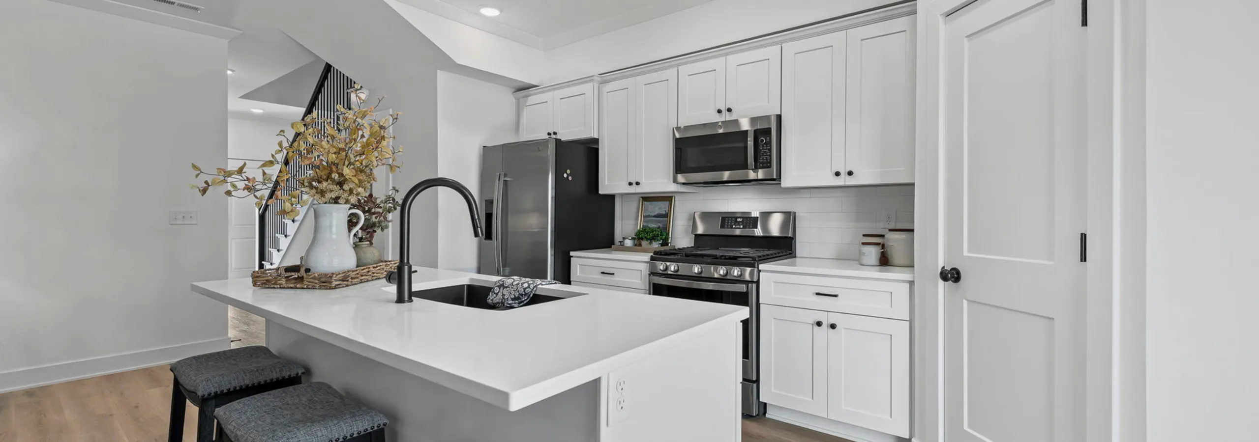 Contemporary kitchen with sleek white cabinetry, stainless steel appliances, and elegant island seating for two.