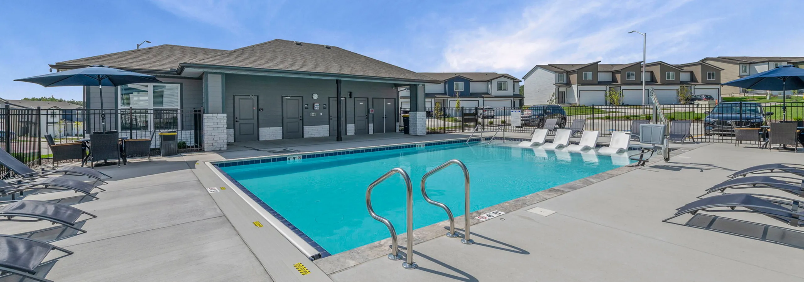 Inviting communal pool area with modern sun loungers, shaded seating, and a serene neighborhood view.