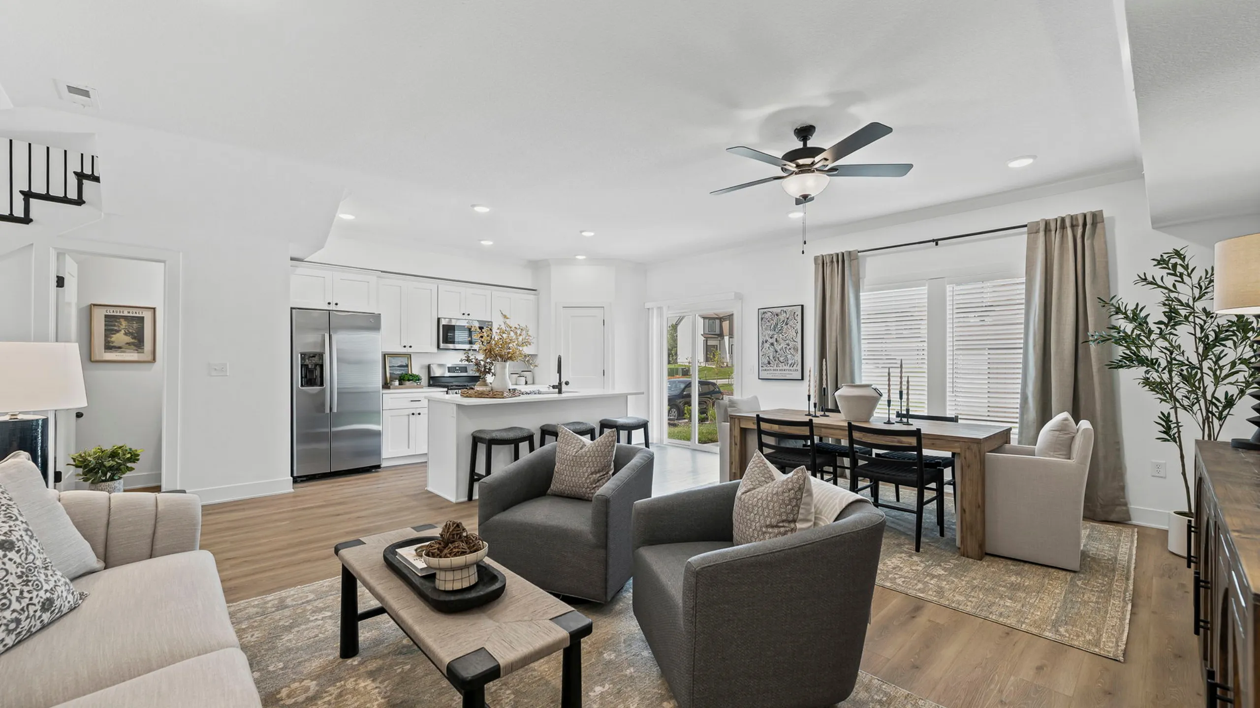 Modern open-plan living area featuring sleek kitchen with stainless steel appliances, cozy seating, and elegant dining space with large windows.