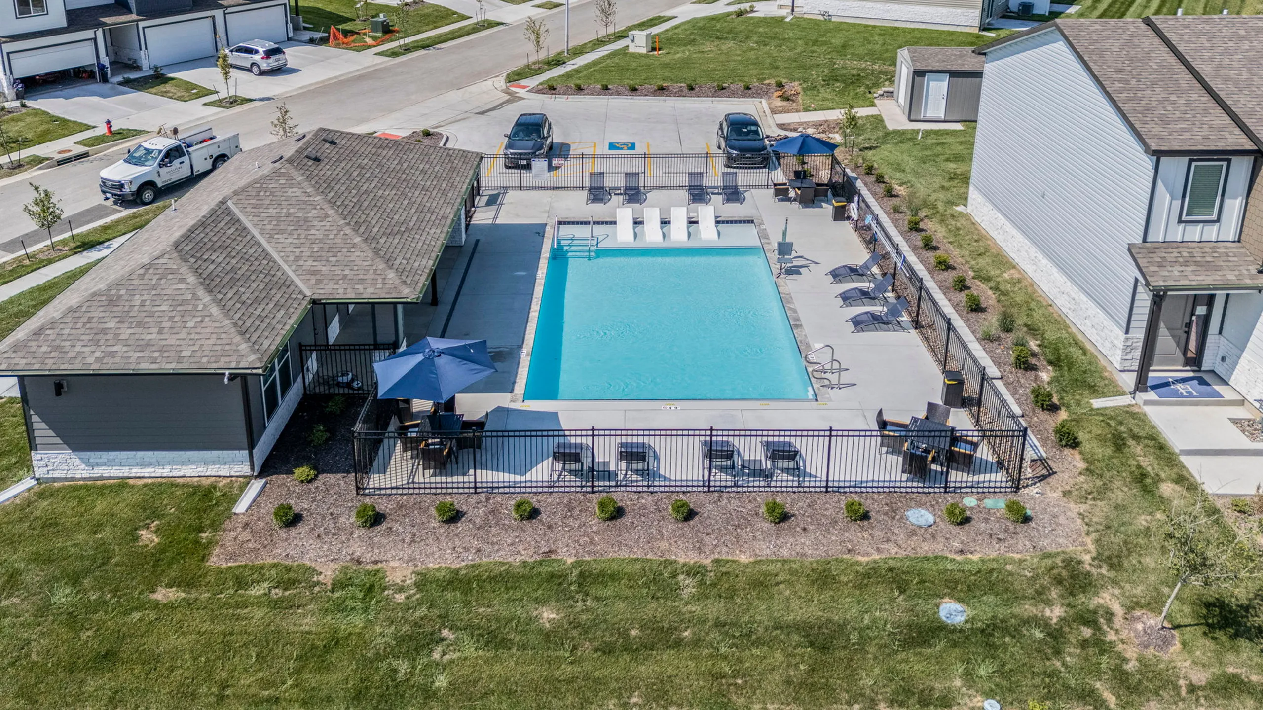 Chic apartment community featuring a refreshing outdoor swimming pool, surrounded by stylish lounge chairs and shaded seating areas.