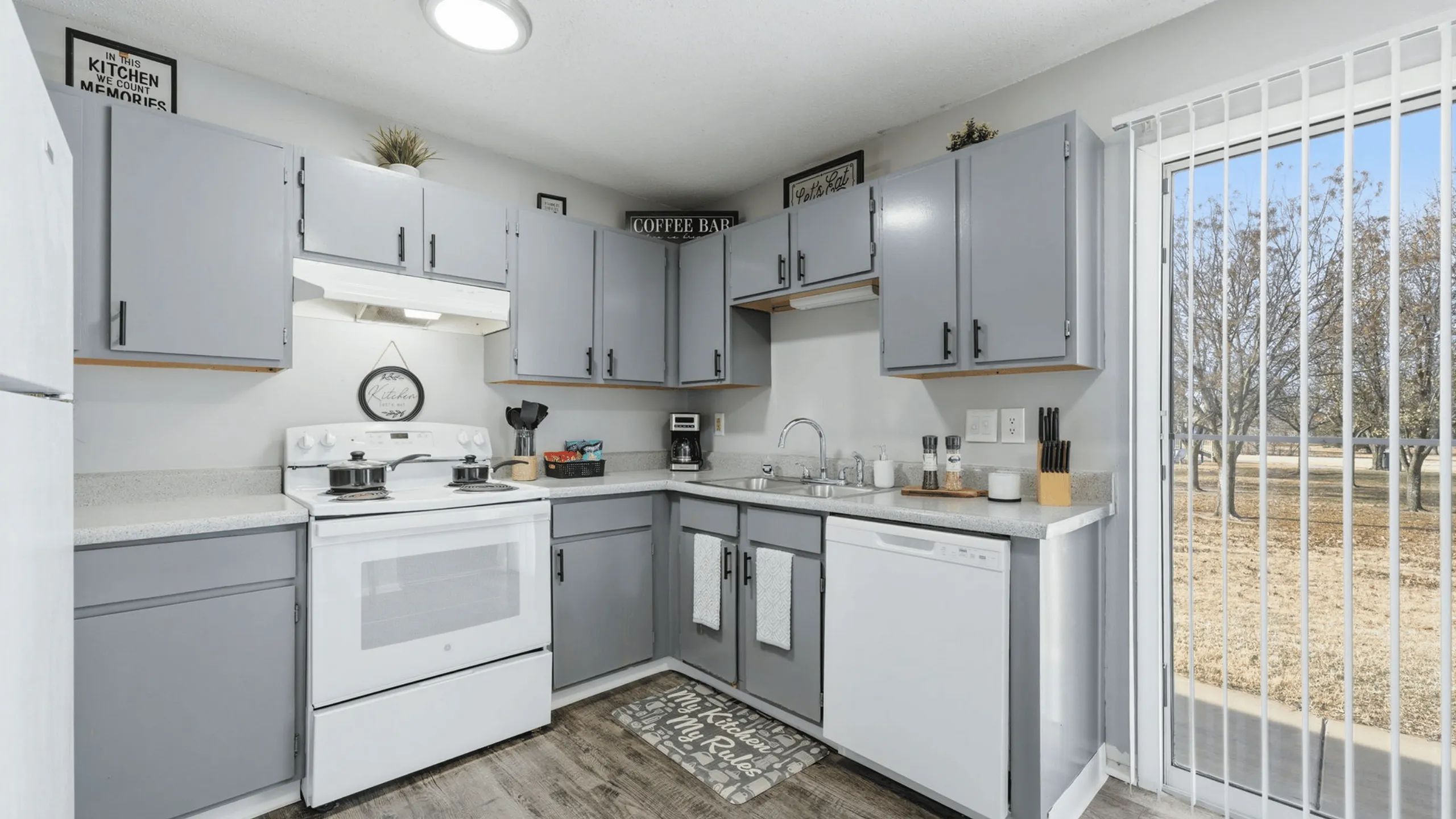 Bright and inviting kitchen with sleek gray cabinets, modern appliances, and a charming breakfast nook overlooking lush greenery.