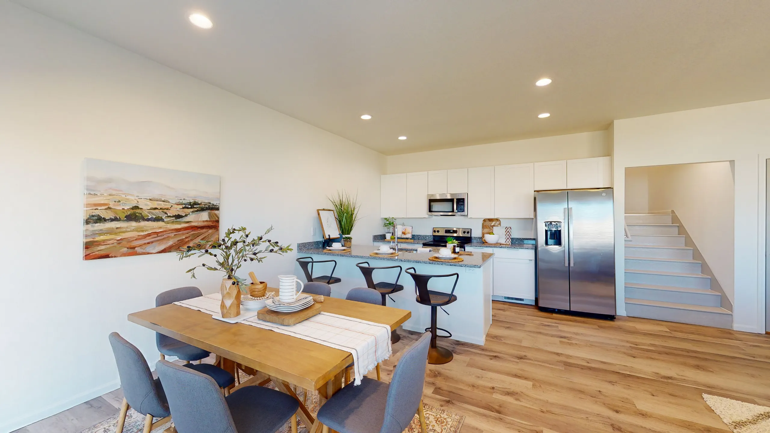 Contemporary open-concept kitchen and dining area featuring a sleek countertop, modern bar stools, and stylish decor.
