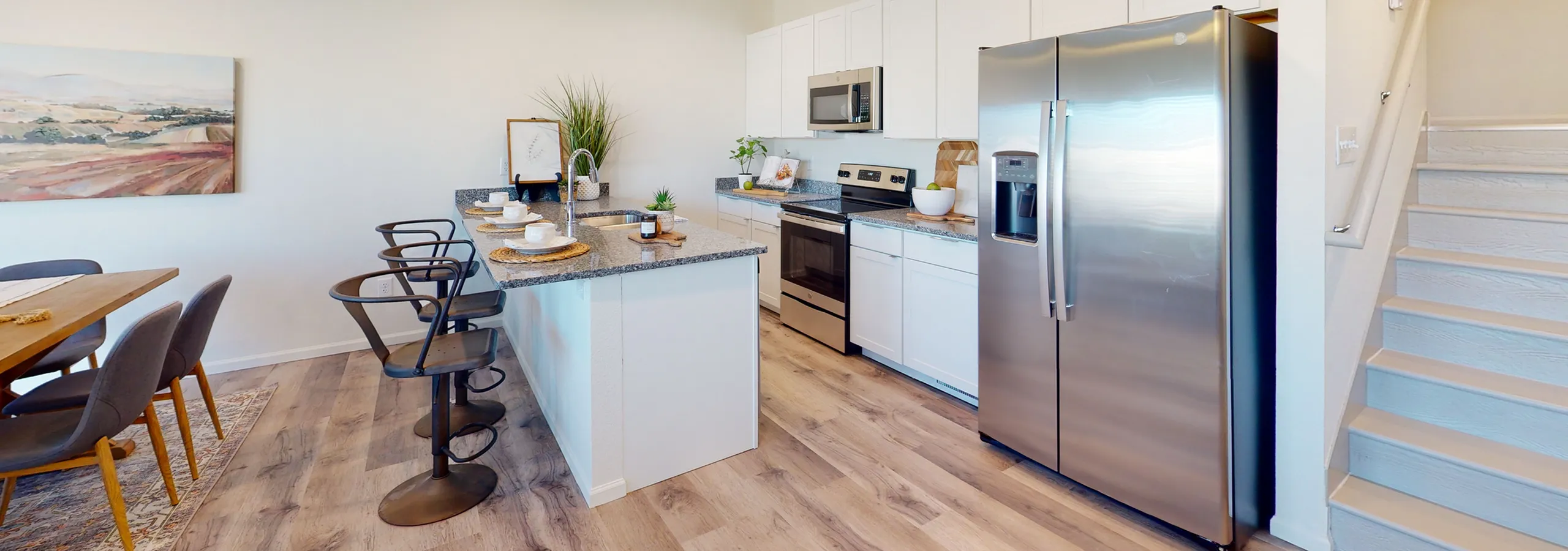 Chic and modern kitchen featuring a sleek island with bar stools, stainless steel appliances, and a cozy dining area with elegant d&eacute;cor.
