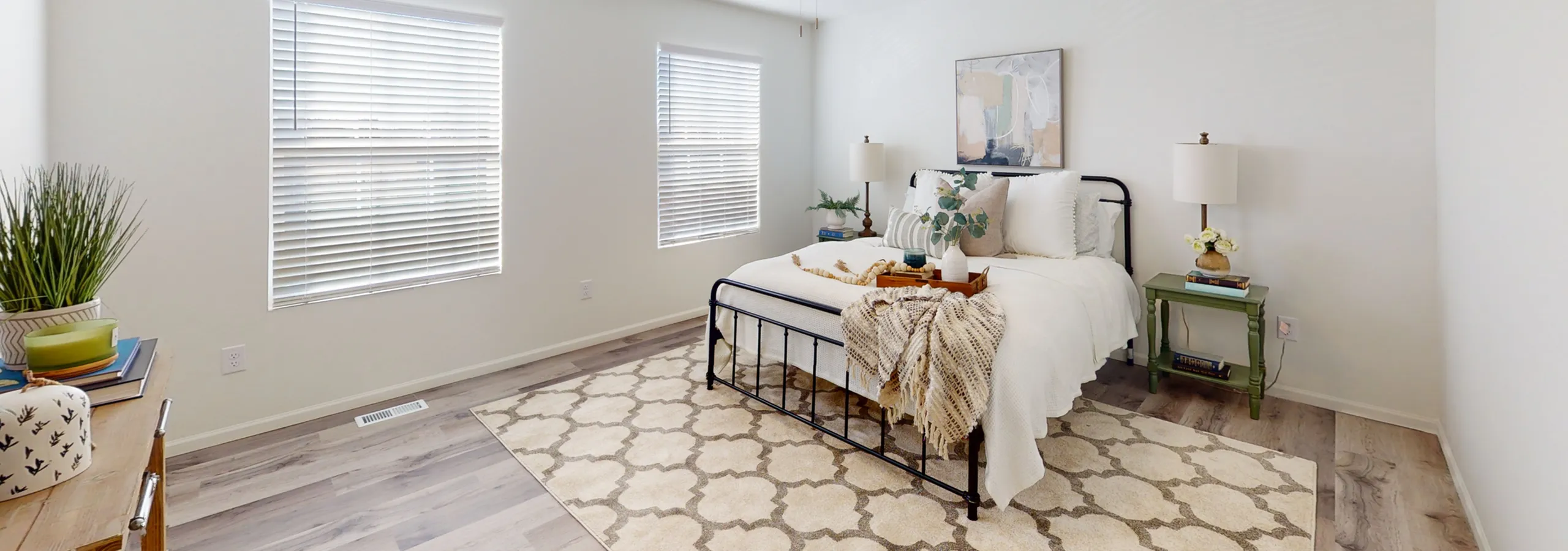 Bright and airy bedroom with modern decor, featuring a cozy bed, stylish artwork, and elegant natural light from large windows.